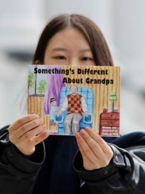 Sasha Au Yong (author) pictured with her book, Something's Different About Grandpa.
